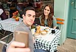 Couple at pavement cafée talking selfie