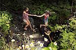 Two female friends crossing stream, Sattelbergalm, Tyrol, Austria