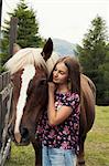 Girl petting palomino horse in field, Sattelbergalm, Tyrol, Austria