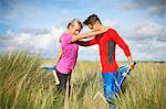 Couple in tall grass on one leg doing stretching exercises