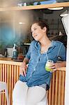 Young woman sitting at bar in cafée, holding juice drink