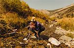 Woman crouching, drinking from creek, Mineral King, Sequoia National Park, California, USA