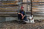 Man with dog resting by wooden cabin, Walton lake, oregon, USA