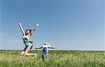 Mother and son jumping for joy in field