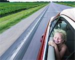 Windswept boy in car eyes closed smiling