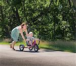 Mother pushing daughter riding tricycle