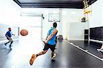 Two male basketball players running and passing ball on basketball court