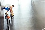 Male basketball player tying trainer laces on basketball court