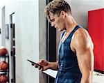 Sweating male basketball player looking at smartphone in changing room