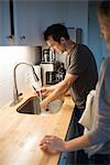 Mid adult couple washing kitchen knife at kitchen sink