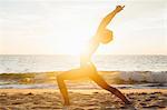 Woman on beach arms raised bending backwards doing stretching exercise