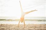 Woman on beach doing handstand
