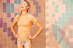 Woman in front of tiled wall hands on hips laughing