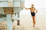 Rear view of woman wearing swimsuit leaning against lifeguard tower