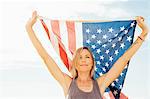 Woman with arms raised holding american flag