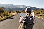 Woman standing in desert road, looking at map, Sedona, Arizona, USA