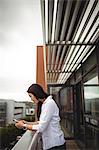Businesswoman using mobile phone at office balcony