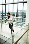 Businesswoman leaning on railing and using mobile phone