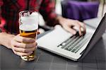 Man using laptop with glass of beer on table