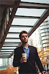 Businessman holding disposable coffee cup and digital tablet