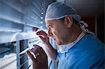 Surgeon looking through window blind at hospital