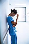 Sad nurse standing in corridor