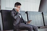 Businessman using digital tablet while talking on mobile phone