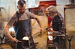 Team of glassblower forming and shaping a molten glass