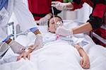 Doctors adjusting oxygen mask while rushing the patient in emergency room