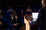 Rear view of female business executive giving a speech