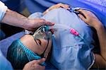 Hands of doctor placing oxygen mask on a pregnant woman face