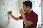 Business executive writing on sticky notes while having cup of coffee