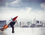 Determined businessman flying with a rocket from the roof of a skyscraper