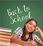 Cute Smiling Hispanic Girl Studying In Front of Back To School Written on Chalk Board.