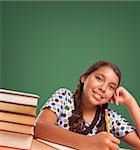 Cute Smiling Hispanic Girl Studying In Front of Blank Chalk Board.