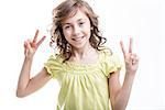 sunny cheerful girl showing a couple of v-signs about peace or victory wearing a yellowish green lovely dress