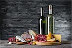 Wine, cheese and meat on a wooden rustic table, food background