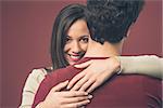 Happy young woman hugging her boyfriend on red background