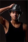 handsome guy in black undershirt and a sequin-covered hat with a very sly smile