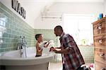 Father And Son Having Fun At Bath Time Together