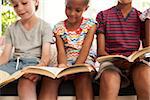 Close Up Of Children Reading On Window Seat