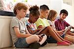 Group Of Children Sit On Floor And Use Technology