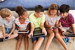 Overhead Shot Of Children Sitting On Floor Using Technology