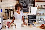 Smiling waitress behind counter at a coffee shop, close up