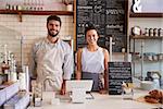 Couple ready to serve behind the counter of a coffee shop