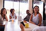 Five adult friends sitting in a cafe, over shoulder view