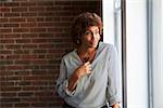 Thoughtful Mature Businesswoman Looking Out Of Office Window