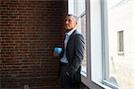 Mature Businessman Standing By Office Window With Coffee