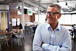 Mature Businessman Standing In Modern Open Plan Office