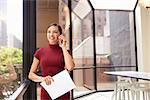 Smiling young white businesswoman on phone in modern office